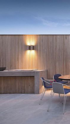 an outdoor dining table and chairs in front of a wooden wall with lights on it