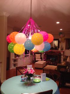 balloons are hanging from the ceiling above a table