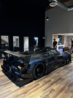 a black sports car is on display in a showroom with people looking at it