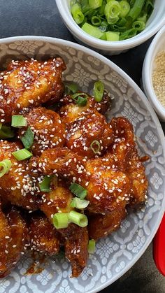 some food is sitting on a plate with sesame seeds and other foods in bowls next to it