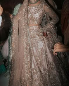 a woman in a bridal gown standing next to other people and looking at her