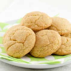 a white plate topped with cookies on top of a green and white table cloth next to a cup