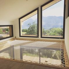 an empty room with three windows and a hammock in the corner on the floor