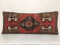 a red and black decorative pillow sitting on top of a white table