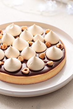 a chocolate dessert with white frosting and nuts is on a plate, ready to be eaten