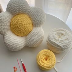 a white plate topped with balls of yarn and a crochet flower