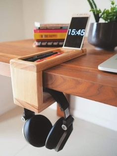 a laptop computer sitting on top of a wooden desk with headphones hanging from it