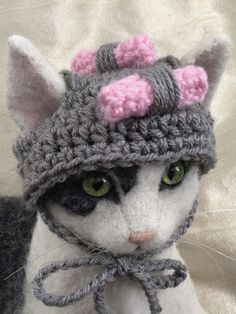 a white cat with green eyes wearing a knitted hat