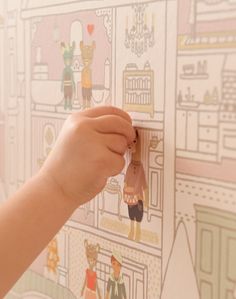 a child's hand is holding a toy in front of a wallpapered background