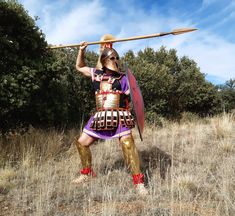 a man dressed in roman armor holding a spear and wearing gladia boots while standing in a field