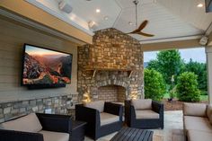 an outdoor living area with couches, chairs and a television mounted on the wall