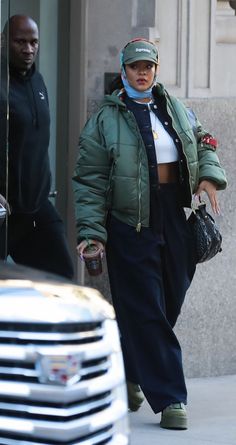 a woman walking down the street wearing a green jacket