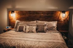 a bed with several pillows and lights on the headboard