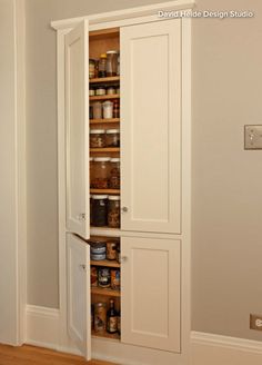 an empty pantry in the corner of a room with wood floors and white walls, filled with spices