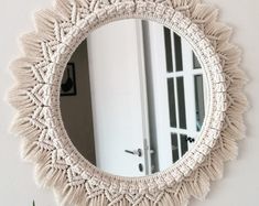 a round mirror hanging on the wall next to a potted plant