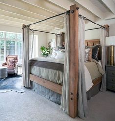 a bedroom with four poster bed and white carpeted flooring in front of windows