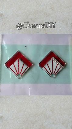 pair of red and white fan shaped earrings on clear plastic package with pink stripe background