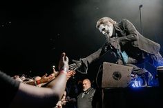 a man in a suit and tie on stage with his hands out to the crowd