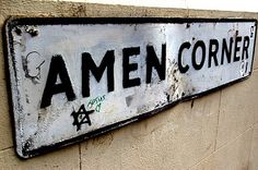 a street sign on the side of a building that says amen corner with graffiti all over it