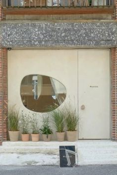 there is a large round mirror on the side of a building with plants in front of it