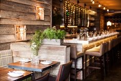 an empty restaurant with tables and chairs in front of wooden walls, plants on the table