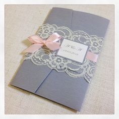 a wedding album with a pink ribbon and lace on the cover is sitting on a table