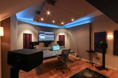 a home recording studio with sound equipment and lights on the ceiling, along with two monitors