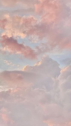 the airplane is flying high in the sky with pink and blue clouds behind it on a cloudy day