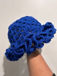 a crocheted blue object being held by someone's hand