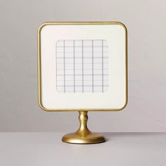 a gold and white square shaped object on a stand with a grid in the middle