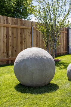 two large rocks sitting in the grass next to a fence