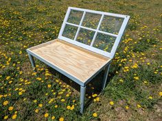 an old window sits in the middle of a field full of dandelions