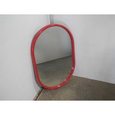 a red mirror sitting on the ground next to a white wall