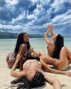 three beautiful women laying on the beach in bikinis