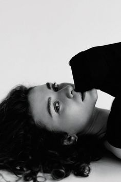 a black and white photo of a woman laying on the floor with her hair in curls