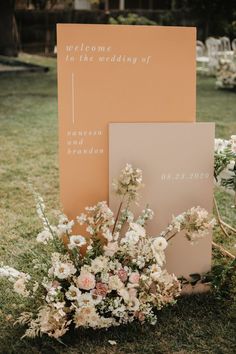 a couple of signs sitting on top of a lush green field next to some flowers