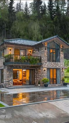 a large house sitting on top of a lush green hillside next to a pool in the rain