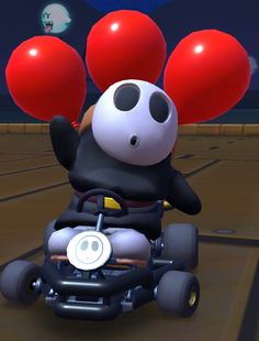 a panda bear riding on the back of a toy car with red balloons attached to it