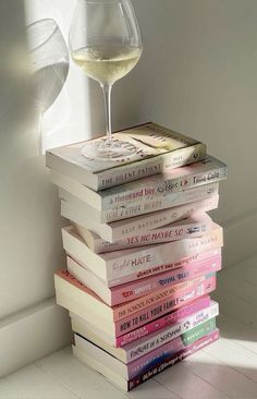 a stack of books with a glass of wine on top