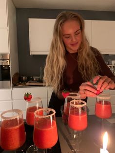 a woman is decorating glasses with strawberries