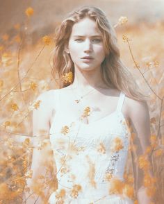 a young woman standing in a field of yellow flowers