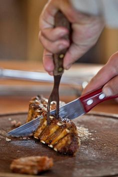 a person cutting meat with a knife and fork