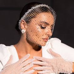 a woman wearing white gloves and a veil