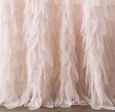 the back of a white curtain with ruffles hanging from it's side