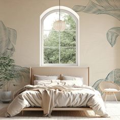 a bed sitting under a window next to a white chair and table with a lamp on it