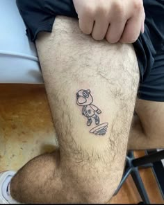 a man with a small tattoo on his leg that has a teddy bear on it