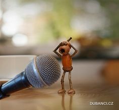 a small figurine is laying on the floor with a microphone in front of it