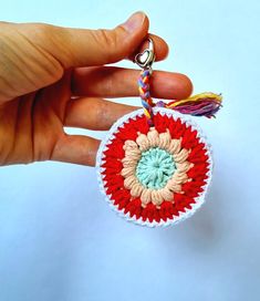 a hand holding a crocheted ornament with a tassel on it