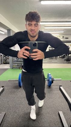 a man taking a selfie with his cell phone in the middle of a gym