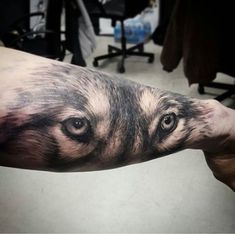 a man's arm with a wolf tattoo on it and his eyes are open